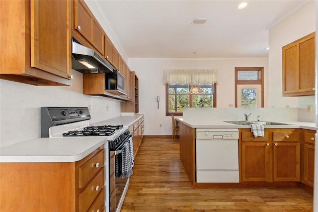 kitchen with sink, range with gas cooktop, kitchen peninsula, dishwasher, and pendant lighting