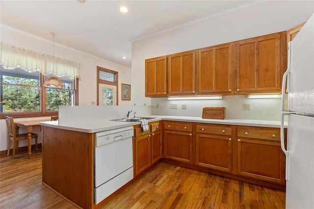 kitchen featuring sink, white appliances, hanging light fixtures, kitchen peninsula, and light wood-type flooring