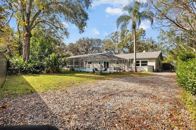 view of front of property with a pool, glass enclosure, and a front yard