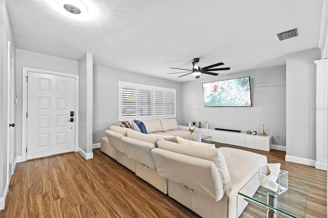 living room with hardwood / wood-style flooring, ceiling fan, and a textured ceiling