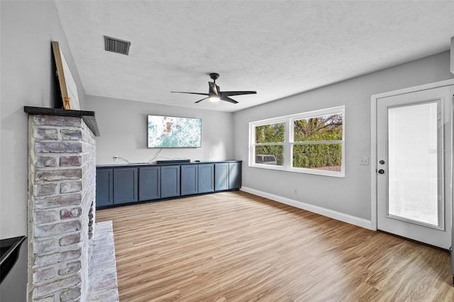 unfurnished living room with ceiling fan, a textured ceiling, and light hardwood / wood-style floors