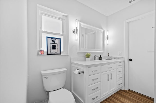 bathroom with hardwood / wood-style flooring, vanity, and toilet