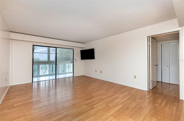 unfurnished room featuring light hardwood / wood-style flooring and a textured ceiling