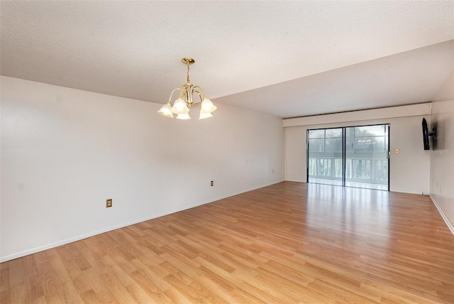 empty room featuring an inviting chandelier, light hardwood / wood-style flooring, and a textured ceiling