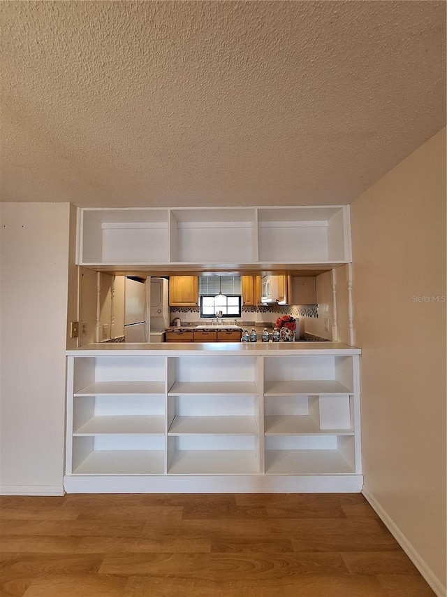 details with wood-type flooring, refrigerator, sink, and a textured ceiling