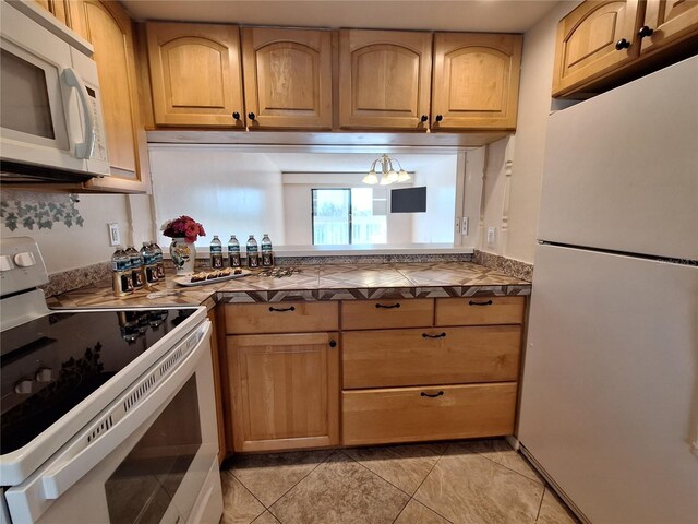 kitchen with white appliances, tile counters, and light tile patterned floors