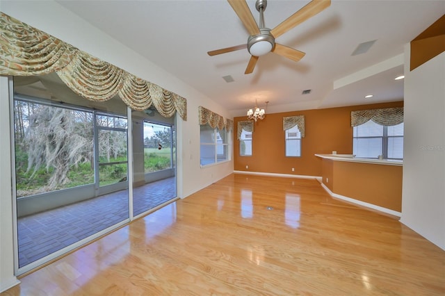 interior space with a healthy amount of sunlight, ceiling fan with notable chandelier, and light hardwood / wood-style floors