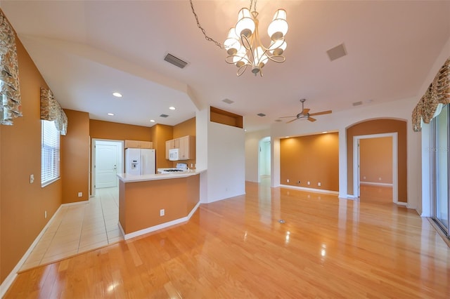 kitchen with ceiling fan with notable chandelier, white appliances, kitchen peninsula, and light hardwood / wood-style floors