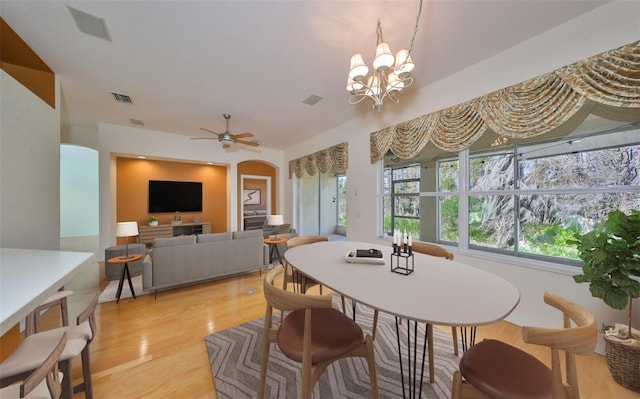 dining area with ceiling fan with notable chandelier and light wood-type flooring