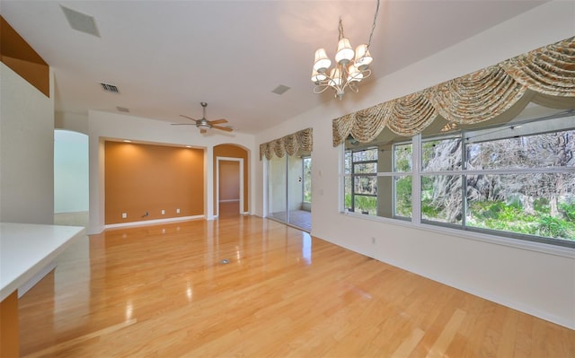 unfurnished living room featuring ceiling fan with notable chandelier and wood-type flooring