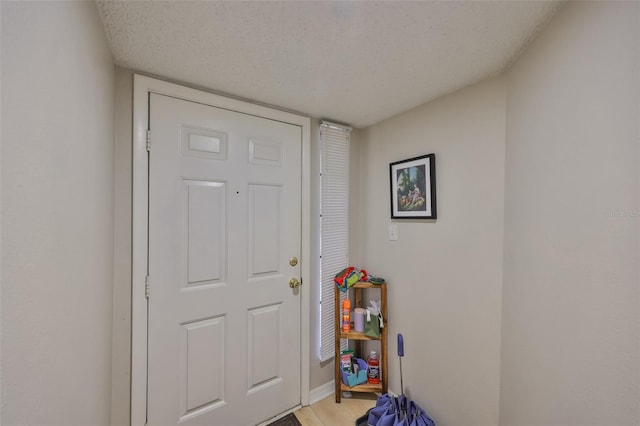 doorway to outside with light hardwood / wood-style floors and a textured ceiling