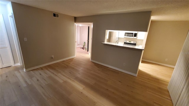 unfurnished living room with light wood-style floors, baseboards, visible vents, and a textured ceiling