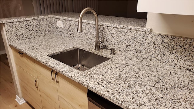 details featuring a sink and light stone countertops