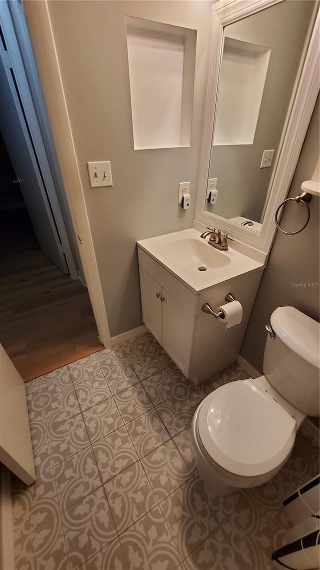 bathroom featuring tile patterned flooring, vanity, toilet, and baseboards