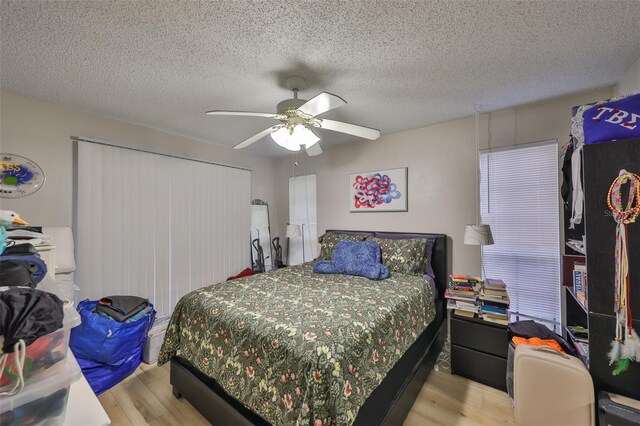 bedroom featuring light wood-type flooring, ceiling fan, a closet, and a textured ceiling