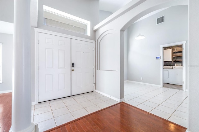 entrance foyer with light tile patterned floors, a towering ceiling, and independent washer and dryer