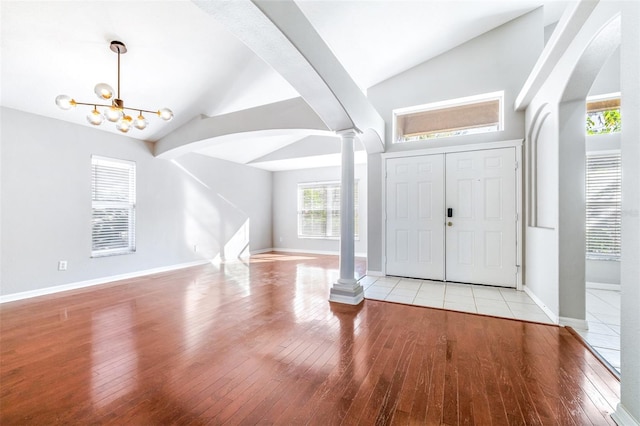 foyer with ornate columns, vaulted ceiling, and light wood-type flooring