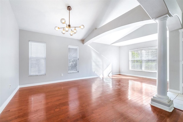 unfurnished living room featuring ornate columns, vaulted ceiling, hardwood / wood-style floors, and an inviting chandelier