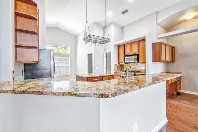 kitchen featuring light stone counters, stainless steel appliances, and kitchen peninsula