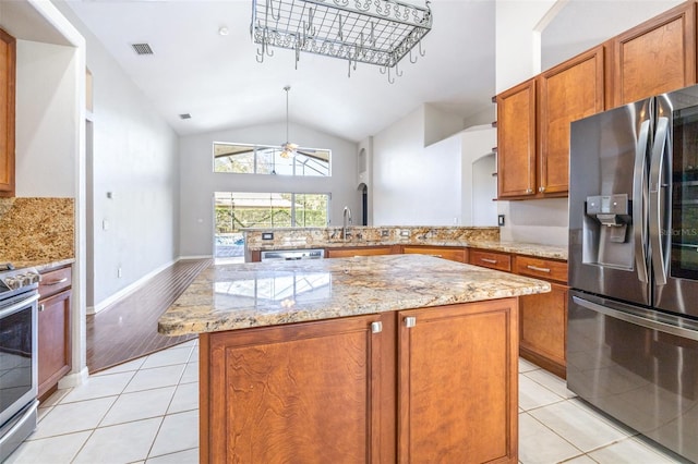 kitchen featuring stainless steel appliances, a center island, light tile patterned flooring, vaulted ceiling, and kitchen peninsula