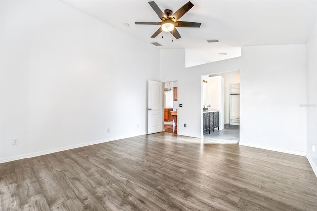 interior space with ensuite bathroom, hardwood / wood-style floors, ceiling fan, and high vaulted ceiling