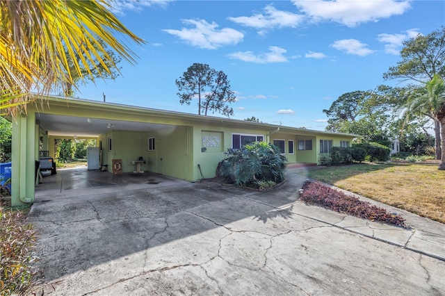 ranch-style home with an attached carport, concrete driveway, and stucco siding