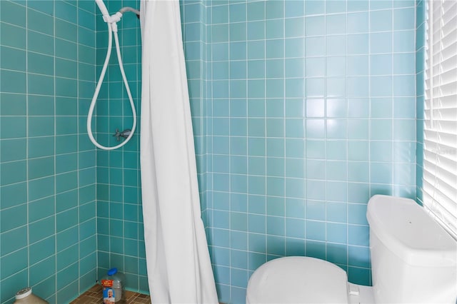 bathroom featuring toilet, curtained shower, and tile walls