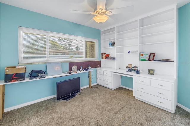 carpeted home office with ceiling fan and built in desk