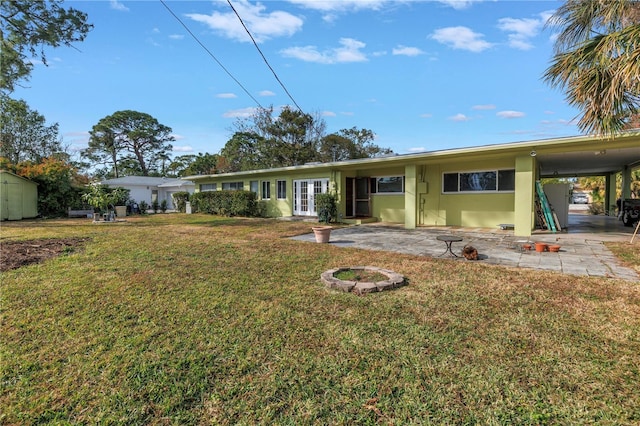 rear view of house with a carport, an outdoor fire pit, a yard, and french doors