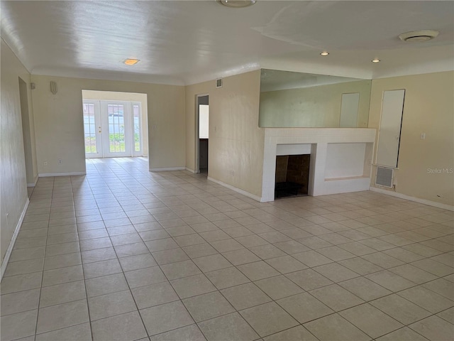 unfurnished room with light tile patterned floors, a brick fireplace, visible vents, and baseboards