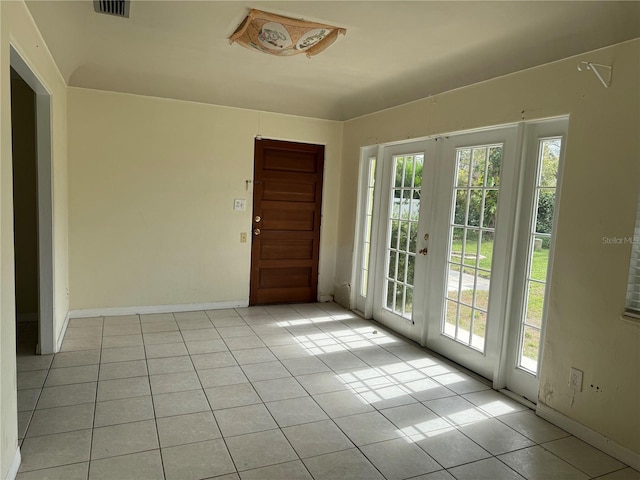 unfurnished room featuring visible vents, french doors, light tile patterned flooring, and a wealth of natural light