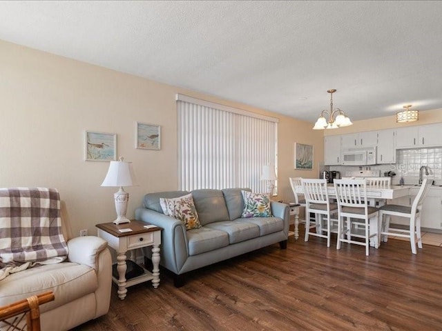 living room featuring plenty of natural light, dark hardwood / wood-style floors, a textured ceiling, and a notable chandelier