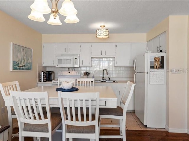 kitchen featuring white cabinetry, sink, white appliances, and backsplash