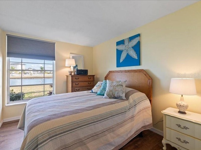 bedroom featuring a water view and hardwood / wood-style flooring