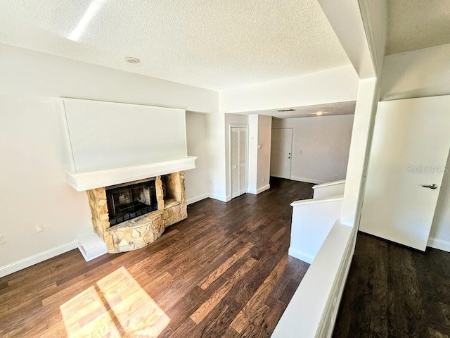 unfurnished living room featuring dark hardwood / wood-style floors, a textured ceiling, and a fireplace