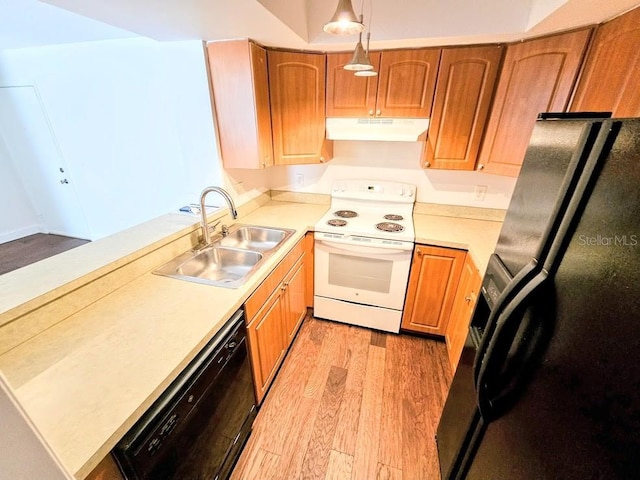 kitchen featuring sink, pendant lighting, light hardwood / wood-style floors, and black appliances