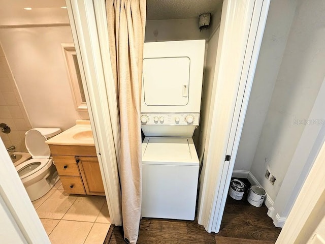 laundry area with stacked washer and dryer and light tile patterned flooring