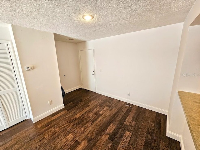 unfurnished room with a textured ceiling and dark hardwood / wood-style flooring