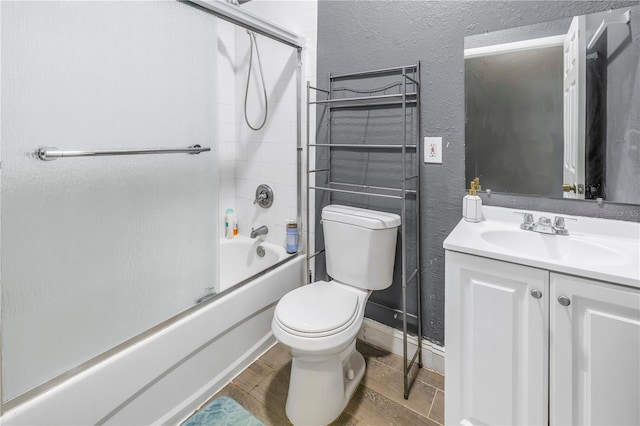 full bathroom featuring hardwood / wood-style flooring, bath / shower combo with glass door, vanity, and toilet