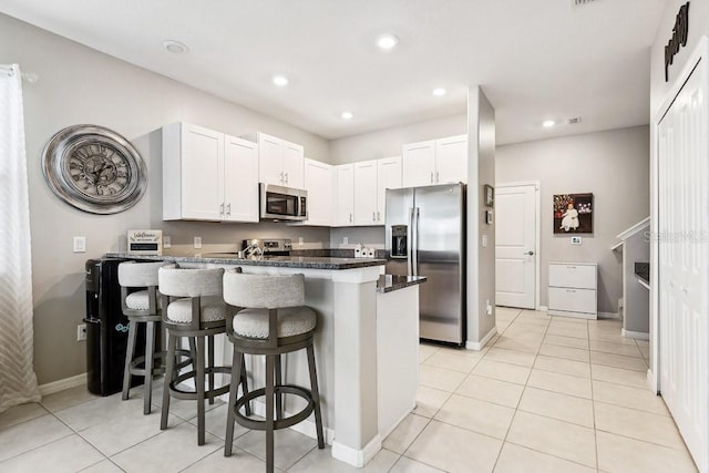 kitchen with stainless steel appliances, a breakfast bar area, white cabinets, and kitchen peninsula