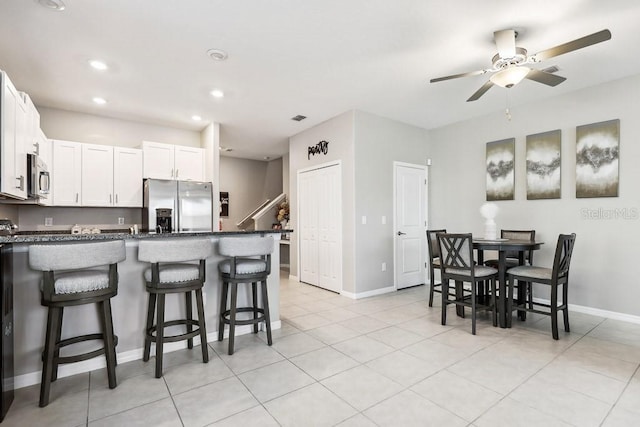 kitchen featuring light tile patterned flooring, appliances with stainless steel finishes, a breakfast bar, and white cabinets