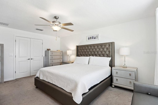 bedroom with light colored carpet, ceiling fan, and a closet