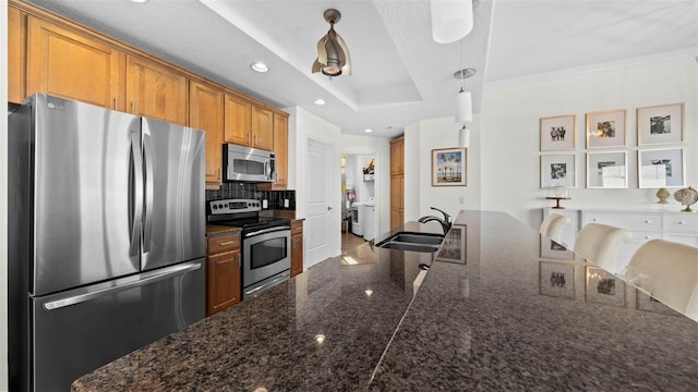 kitchen featuring a breakfast bar, pendant lighting, sink, a tray ceiling, and stainless steel appliances