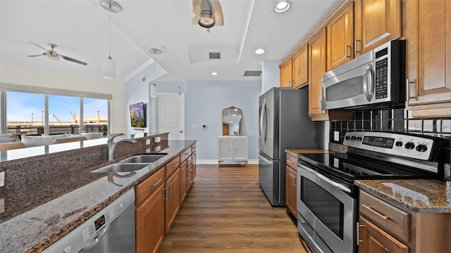 kitchen with dark wood-type flooring, sink, tasteful backsplash, dark stone countertops, and stainless steel appliances