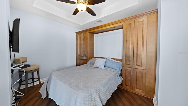 bedroom featuring a raised ceiling, dark hardwood / wood-style floors, and ceiling fan