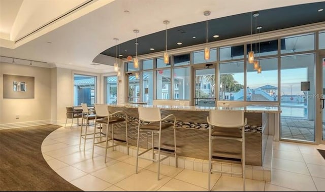 bar with light tile patterned floors, hanging light fixtures, crown molding, and light stone counters