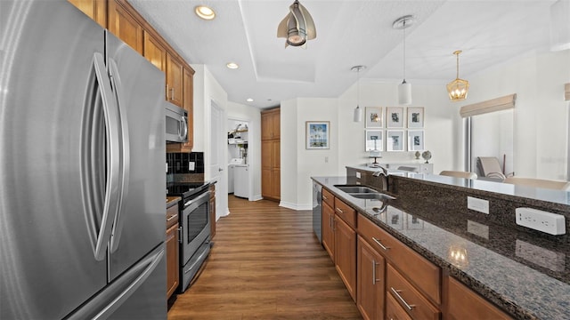 kitchen featuring stainless steel appliances, dark hardwood / wood-style flooring, sink, dark stone countertops, and pendant lighting