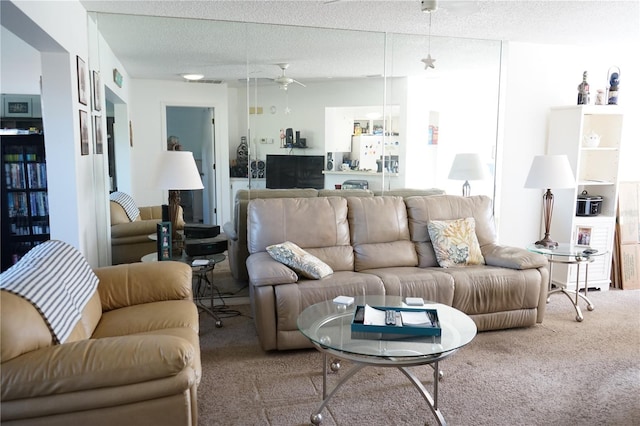 living room with carpet flooring, a textured ceiling, and ceiling fan