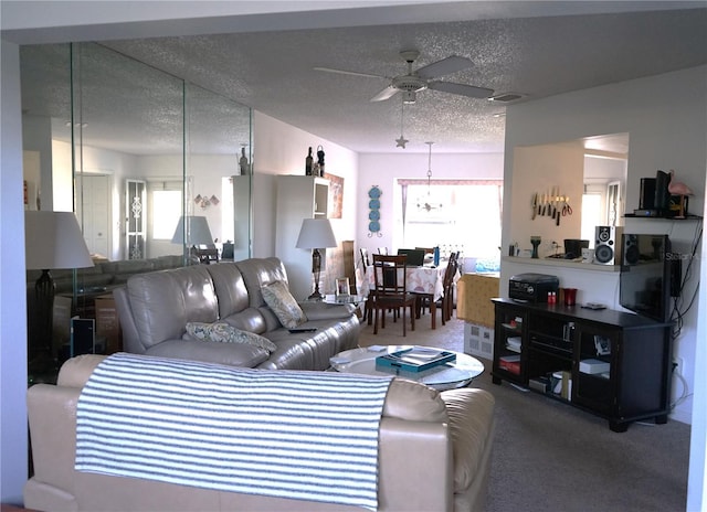 carpeted living room featuring ceiling fan with notable chandelier and a textured ceiling