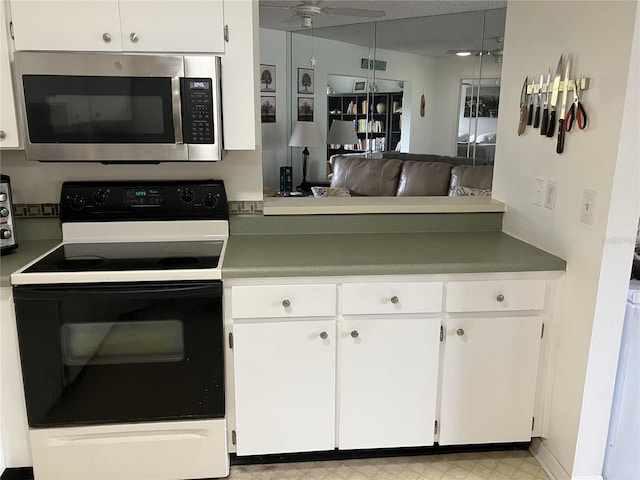 kitchen featuring black electric range oven, hanging light fixtures, and white cabinets